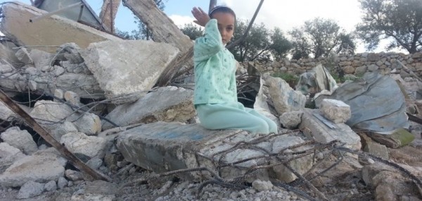 A child sits on top of her demolished home