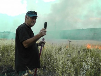 Illegal Shilo settler Moshka takes pictures of his handiwork, torching Palestinian land. (Photo by ISM)