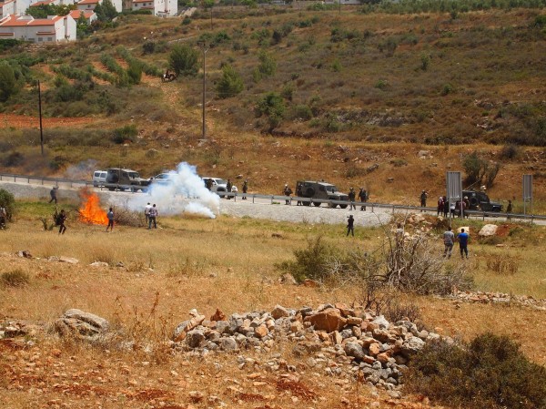Israeli forces shoot tear gas canisters at protesters setting the land on fire (Photo by ISM)