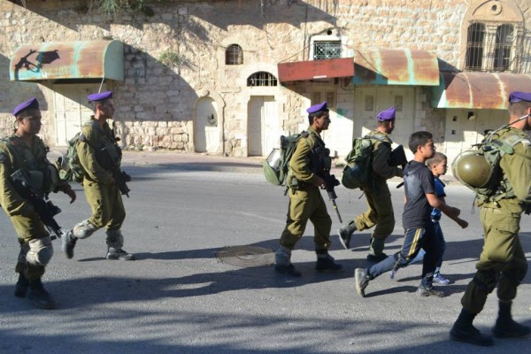 Soldiers escorting children down Shuhada Street