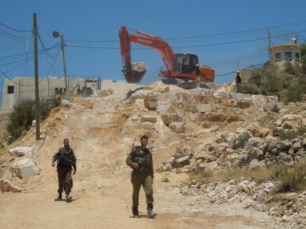 Israeli military guard bulldozer working on Palestinian land