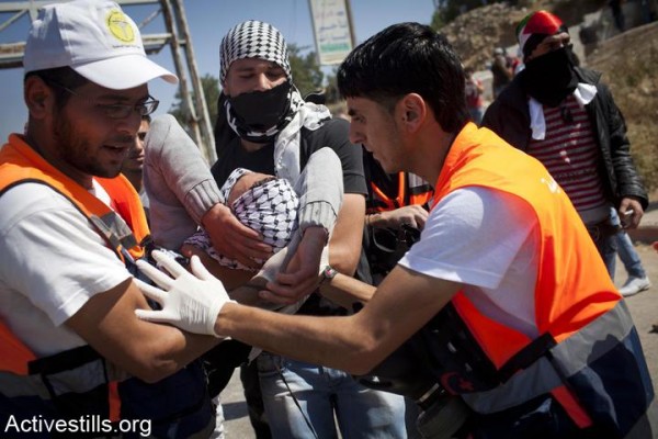 Palestinian medics evacuate a Palestinian youth after he was shot by Israeli soldiers during clashes at Ofer prison (Photo by Activestills)