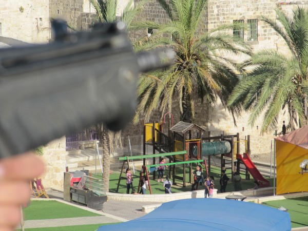 Soldier on rooftop pointing gun near playground - (Photo by ISM)