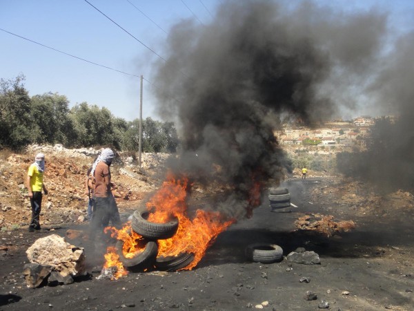 Tyre fires on the main blocked road to Nablus, with Qedumim illegal settlement visible in the background (Photo by ISM)