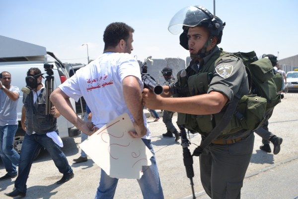 Israeli Border Police officer pushing back a journalist (Photo by ISM)