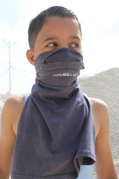 A boy wears his shirt as a mask to protect against tear gas. (Photo by Joe Catron)