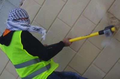 Palestinian activist smashes annexation wall with a sledgehammer (photo by Ingrid Bousquet).