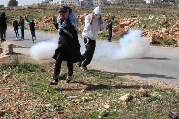 Palestinians taking cover from stun grenades fired by Israeli forces. 7th March 2014