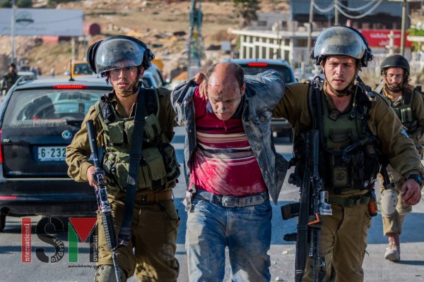 An injured Palestinian man being taken away by soldiers