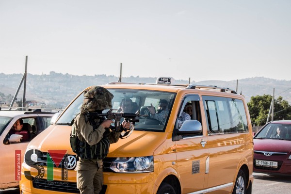 An Israeli soldier using a taxi full of people as a shield