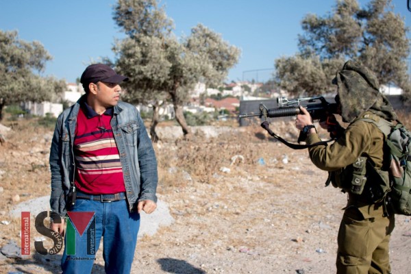 Israeli soldier pointing his gun in the face of a Palestinian man