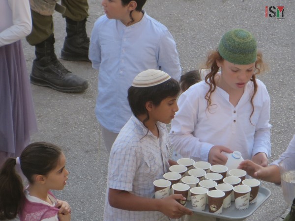 Israeli settlers and soldiers sharing tea at the scene of the execution of Fadel al-Qawasmeh