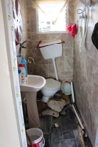 The bathroom in Fatima Abdel Aziz Qudaih's home with the floor broken from the pressure of the floods. Photo credit ISM