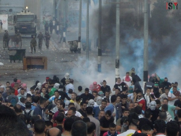 Palestinians running from the tear-gas