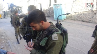 Israeli soldier writing down passport number of an international