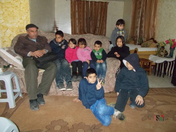 Friend Nuredin Amro and his son, Abedkarim sit on the far left side. Seven of the children who live in this house are, from left to right: Mira, Mayaan, Ahmad, Yara. On top, Fajer. On the floor, Mohammad and Badar.