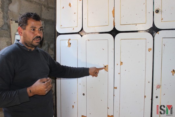Amar points out effects of shrapnel on his cupboard