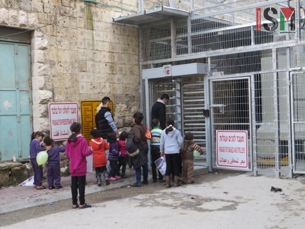 Children waiting to cross back into their 'closed military zone' neighbourhood