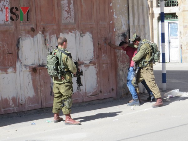 Israeli forces aggressively body-searching young Palestinian man