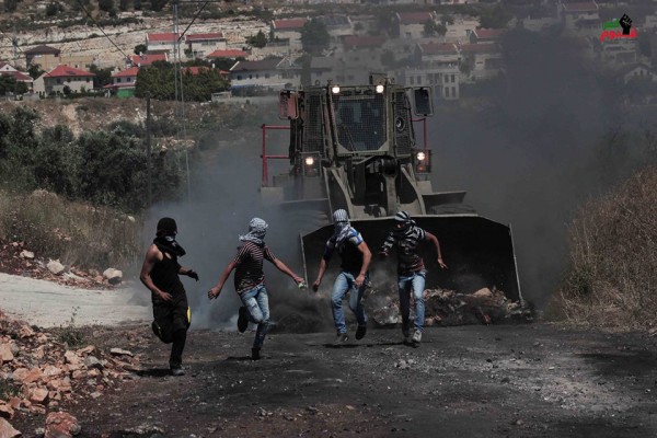 Israeli forces chasing demonstrators, illegal settlement can be seen in the back