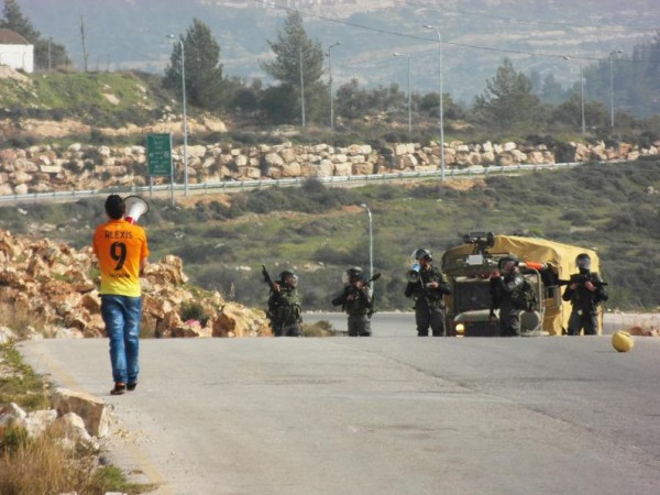 Youth approaching Israeli soldiers on the road to the natural spring