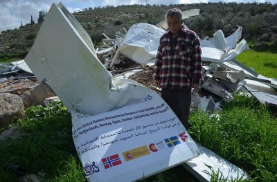 Mohammed Tomazi stands next to his destroyed home 