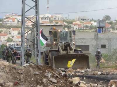 Israeli border police officers and armored bulldozer invading the village during a demonstration, April 2013 (Photo by ISM)
