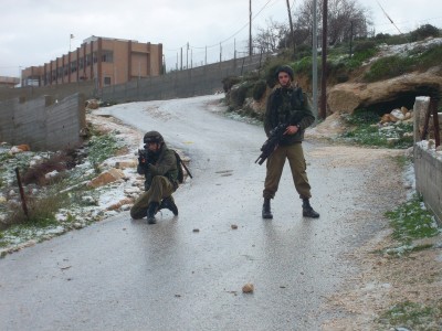 Israeli soldier pointing at residents of Urif with a M16 rifle charged with rubber coated steel bullets during a settler attack last January (Photo by ISM) 