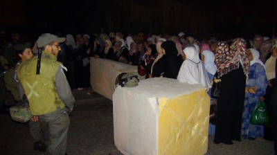 Palestinian women waiting in the queu for Israeli soldiers to let them through the checkpoint (Photo by ISM)