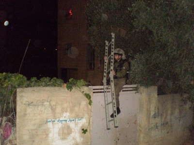 Israeli soldier climbing fence surrounding the Palestinian home. The door was unlocked the entire time (Photo by ISM)