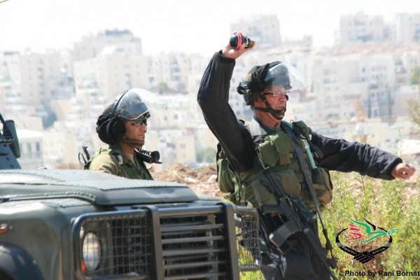 A soldier throwing a tear grenade towards demonstrators (Photo by Rani Bornat)