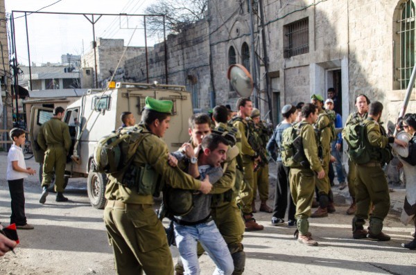 Israeli soldiers restrain one of the settlers responsible for the attack (Photo by ISM)