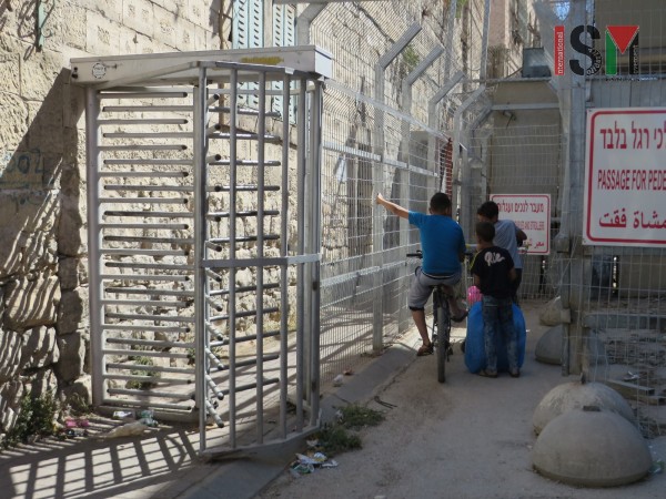 Palestinian children forced to wait at a checkpoint for soldiers to allow them to pass