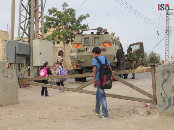 Palestinian schoolchildren forced to squeeze past armored Israeli jeep on their way to school