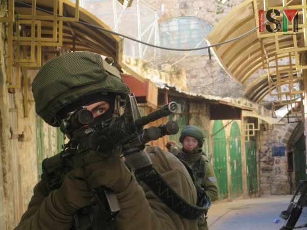 Israeli soldier 'ordering' Palestinians to stop by pointing his gun