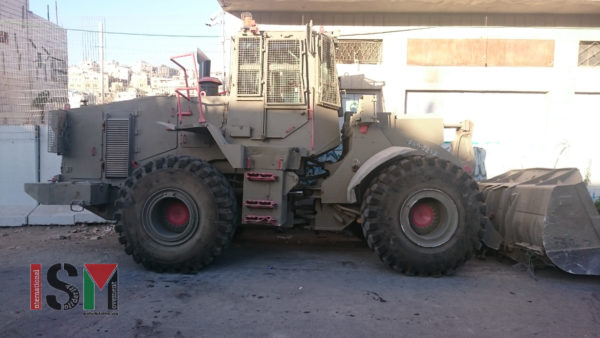 An armored bulldozer rolls out of the Salaymeh checkpoint through the Palestinian neighborhood to create a roadblock off of a narrow side street.