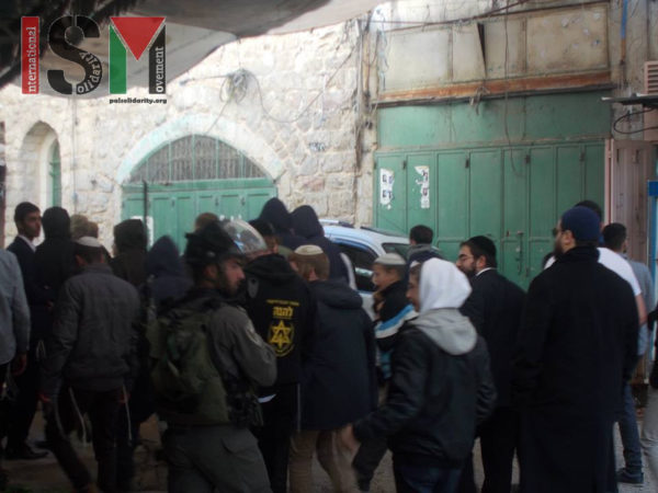 Soldiers and settlers parading through the Palestinian market where some shops closed early