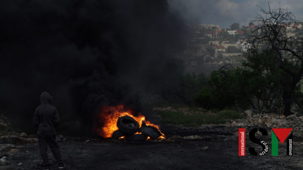 fire of tires burning, black smoke, settlement in the background