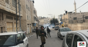 Soldiers invade Al-Khalil, bombarding the city with tear gas and stun grenades. Tear gas is seen in the background.