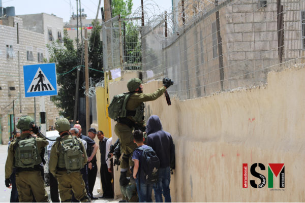 Soldier standing on another soldier taking pictures into a school