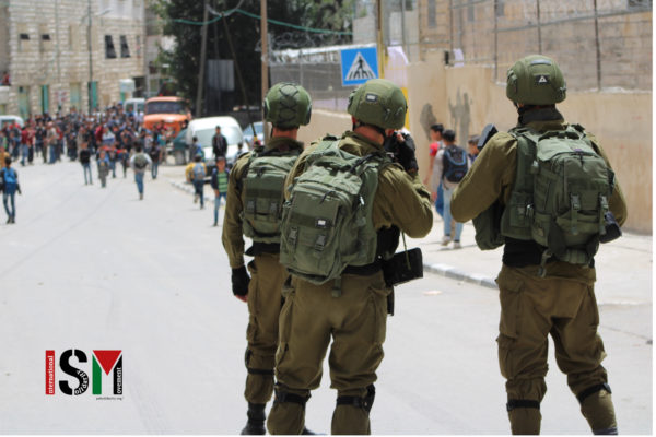 soldiers in focus, big group of children further away