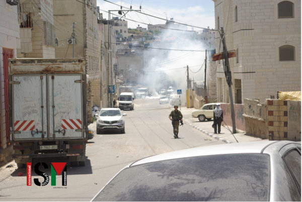 Soldier walking, big cloud of tear gas in the background