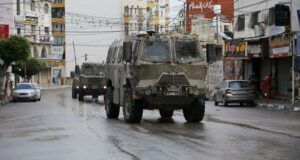 Several Israeli military vehicles driving down the street in Tulkarem