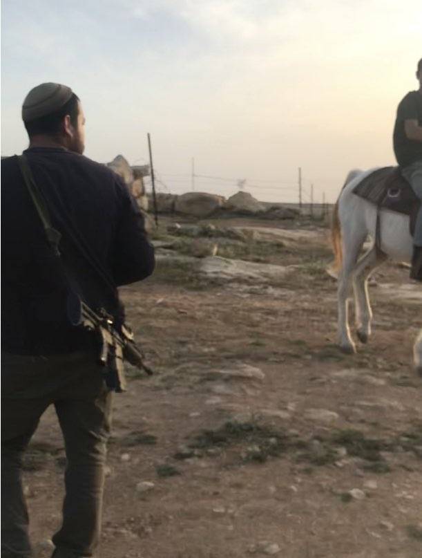 Armed settler guards settler on horseback in Abed's land