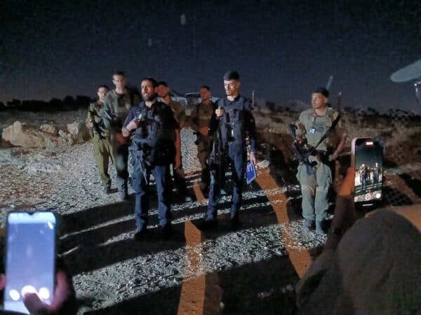 Two cell phone cameras record uniformed officers in a Palestinian village.
